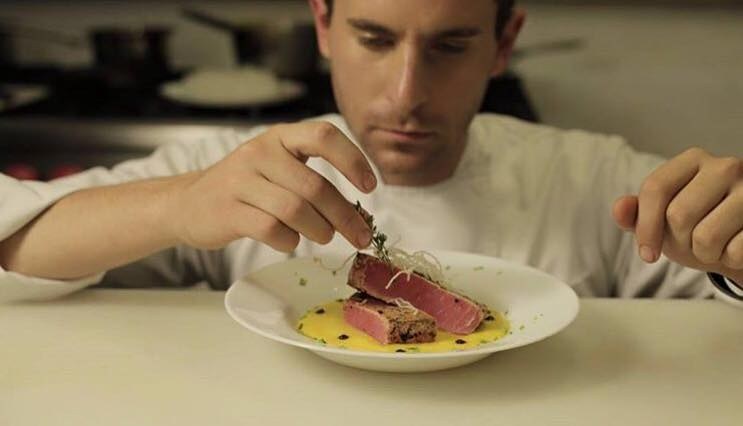 El chef emplatando un tataki de atún en la cocina