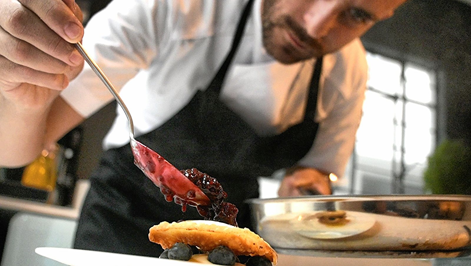 El chef terminando un postre con salsa de frutos rojos