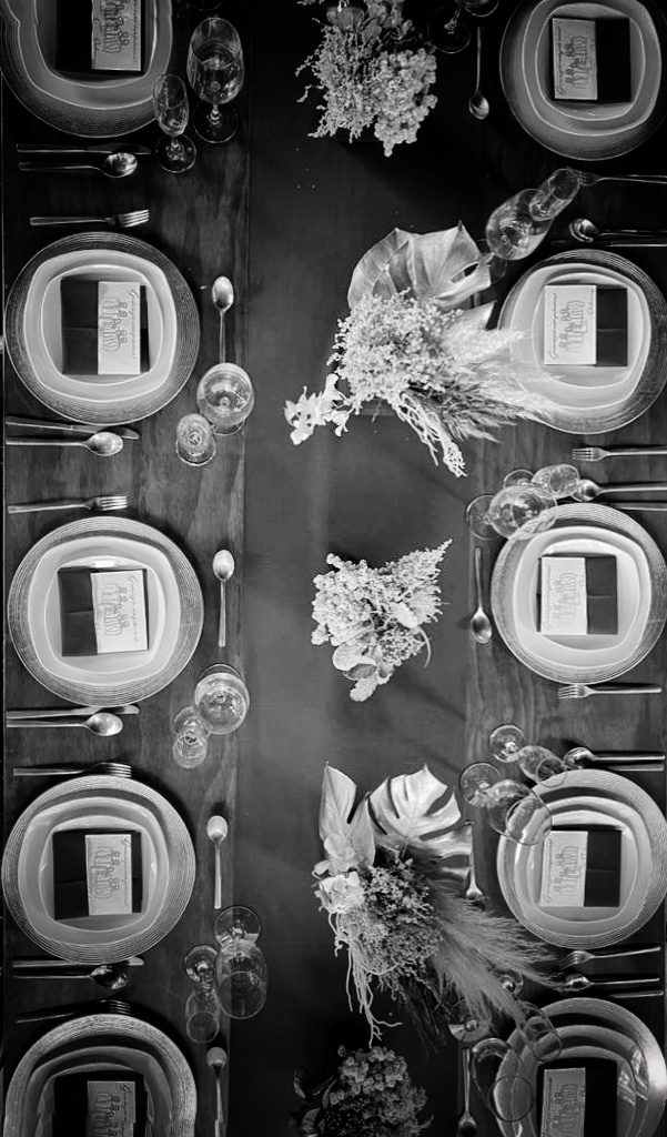 Vista cenital de mesa con platos y arreglos florales en blanco y negro