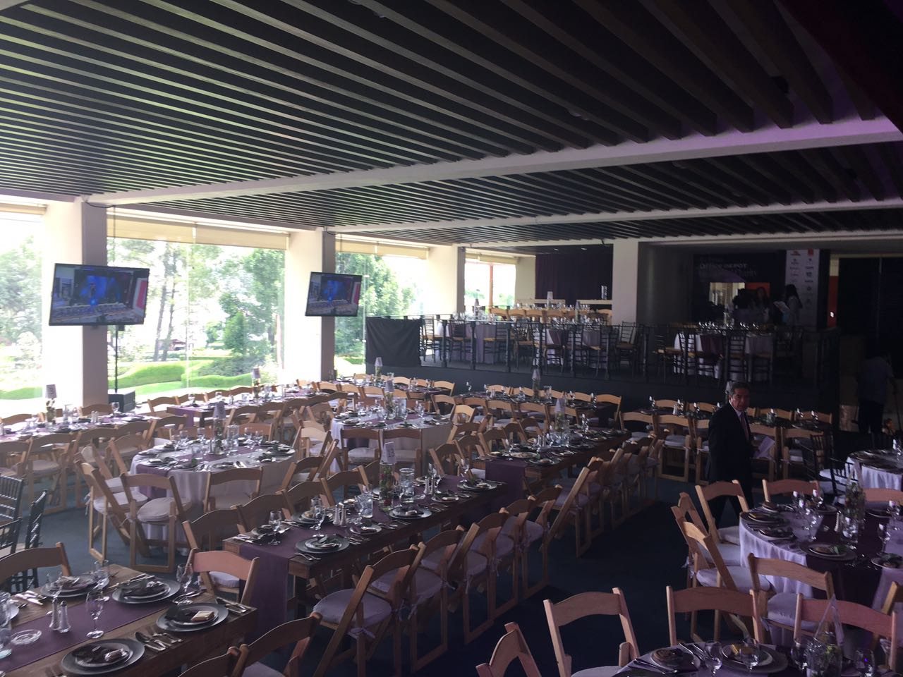 Salón montado para evento corporativo con mesas redondas e imperiales