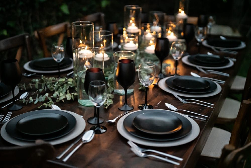 Mesa con vajilla negra, velas flotantes y eucalipto