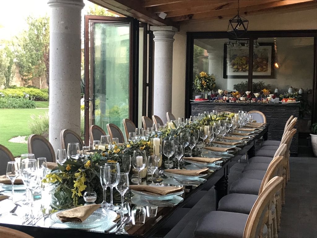Mesa imperial en terraza con columnas y camino de flores amarillas